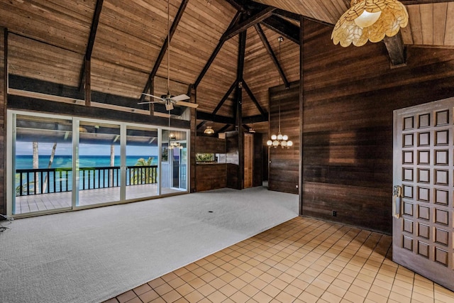 carpeted spare room with wooden walls, beam ceiling, a water view, high vaulted ceiling, and wooden ceiling