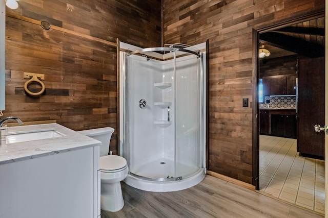 bathroom featuring vanity, wood walls, toilet, and a shower with shower door