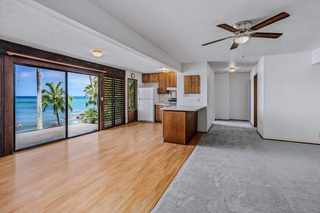 kitchen with light wood-type flooring, white fridge, ceiling fan, and a water view