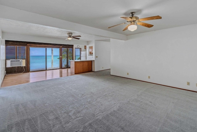 unfurnished living room with cooling unit, ceiling fan, a water view, and light colored carpet