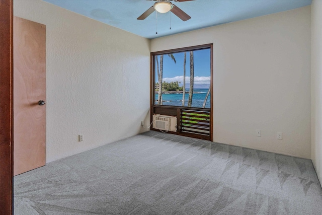 empty room with carpet, a water view, a wall mounted air conditioner, and ceiling fan