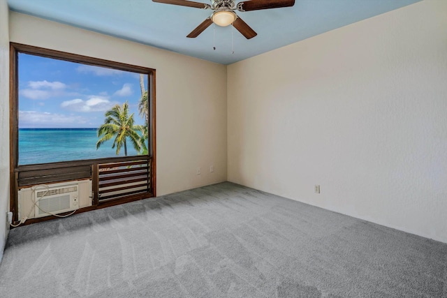 spare room with a wall mounted AC, carpet floors, a water view, and ceiling fan