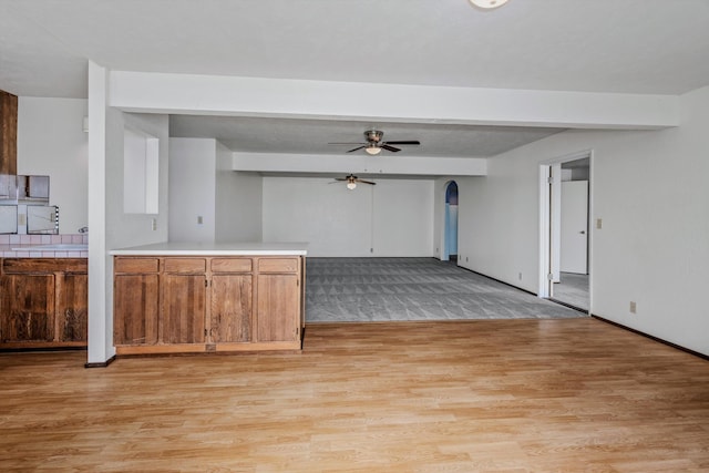 kitchen featuring beam ceiling, light wood-type flooring, and ceiling fan