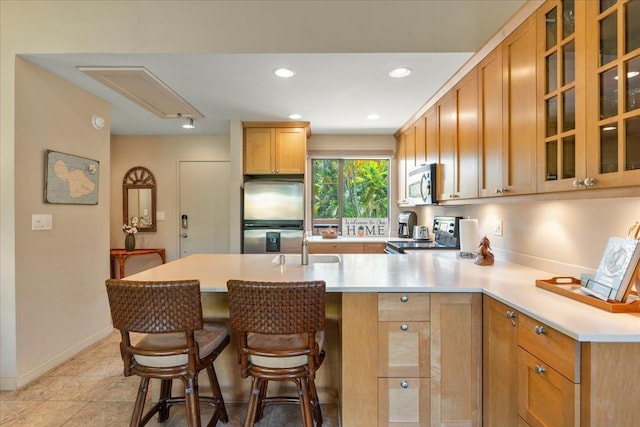 kitchen with glass insert cabinets, a peninsula, stainless steel appliances, light countertops, and recessed lighting