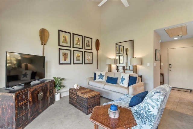 carpeted living area with attic access, a high ceiling, and ceiling fan