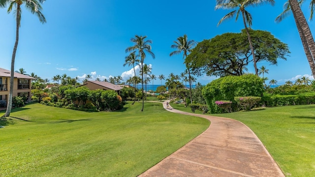 view of community featuring view of golf course and a yard