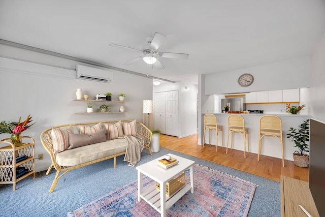 living area featuring light wood finished floors, ceiling fan, and an AC wall unit