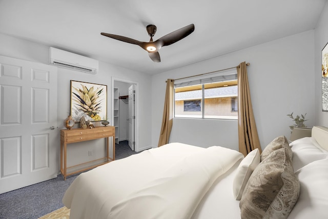 bedroom with a spacious closet, a wall mounted AC, a ceiling fan, and carpet