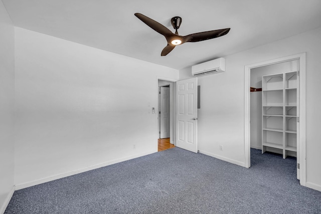 unfurnished bedroom with a ceiling fan, carpet, a wall mounted AC, baseboards, and a spacious closet