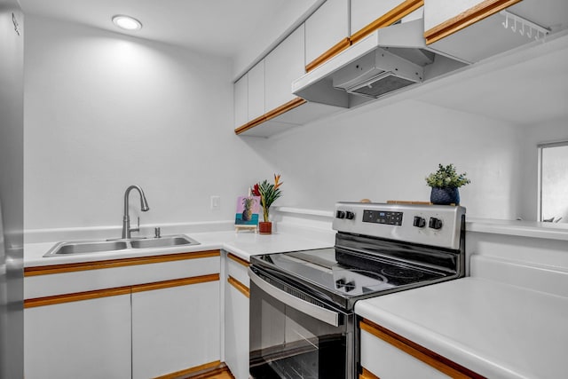 kitchen featuring a sink, under cabinet range hood, stainless steel electric range oven, light countertops, and white cabinets