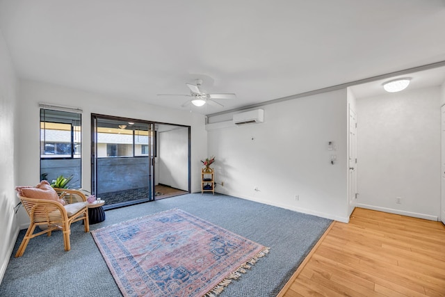 living area with light wood-style floors, baseboards, ceiling fan, and an AC wall unit
