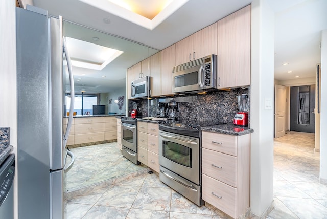 kitchen featuring light brown cabinetry, stainless steel appliances, backsplash, and light tile floors