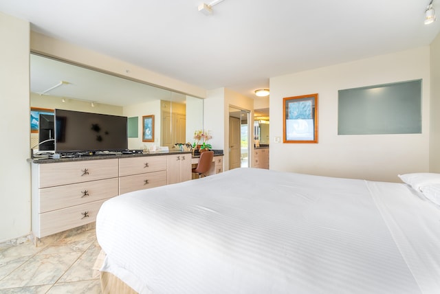 bedroom featuring ensuite bath, rail lighting, and light tile floors