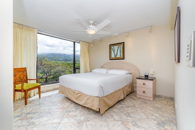 tiled bedroom with ceiling fan, expansive windows, a mountain view, and multiple windows