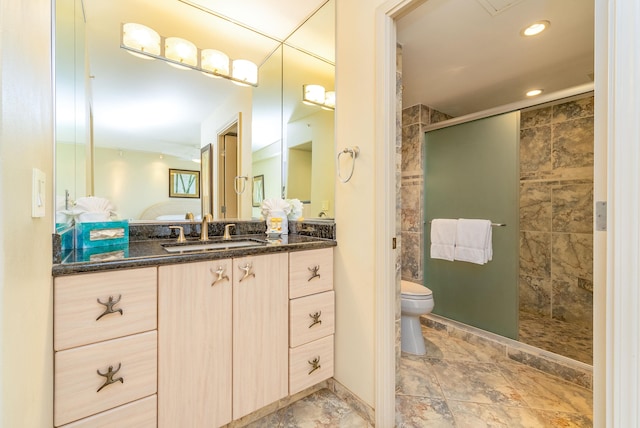 bathroom featuring toilet, vanity, a shower with door, and tile flooring