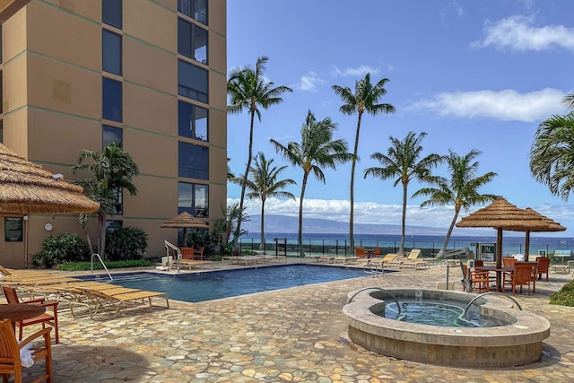 view of pool with a community hot tub, a mountain view, and a patio area