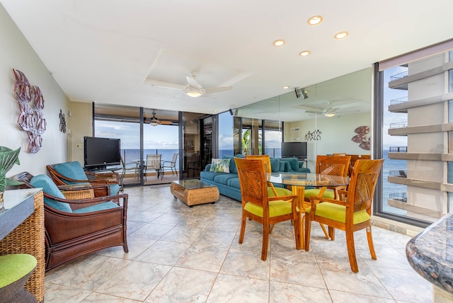 dining area with a water view, expansive windows, ceiling fan, and light tile floors