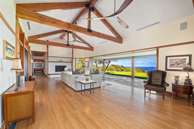 living room with a large fireplace, high vaulted ceiling, beamed ceiling, and light wood-type flooring