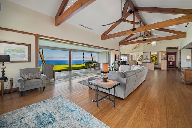 living room with high vaulted ceiling, hardwood / wood-style floors, a water view, and a healthy amount of sunlight