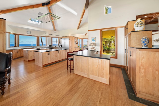 kitchen with sink, beam ceiling, light hardwood / wood-style flooring, and a kitchen island