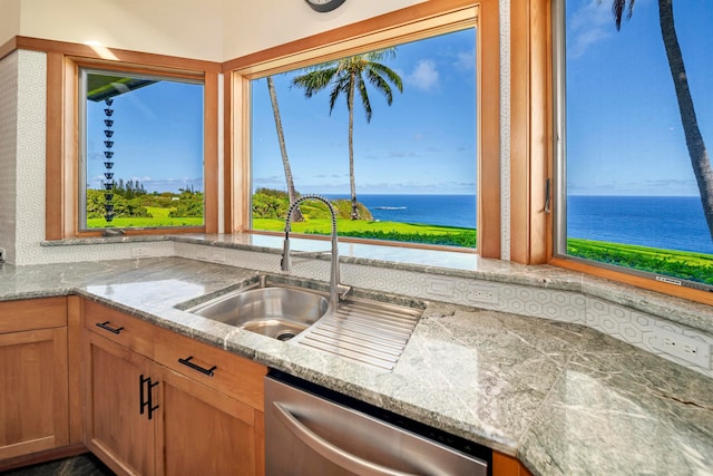 kitchen featuring a water view, light stone counters, dishwasher, and sink