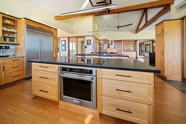 kitchen with a kitchen island, an AC wall unit, stainless steel appliances, lofted ceiling with beams, and light wood-type flooring