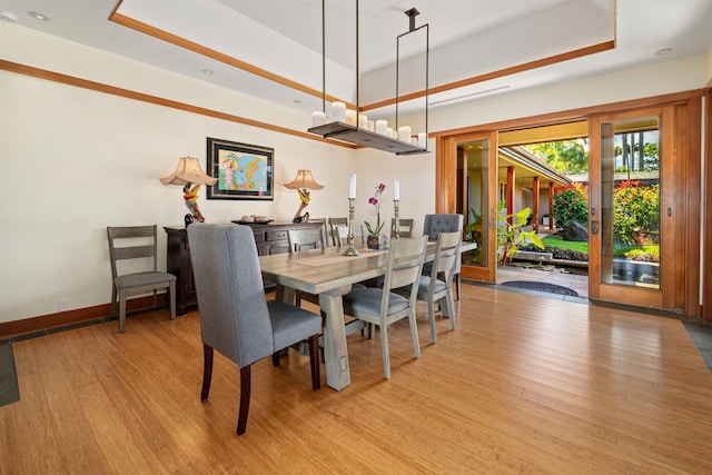 dining area with a raised ceiling and light hardwood / wood-style flooring