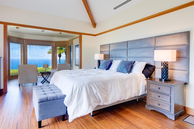 bedroom featuring light hardwood / wood-style flooring, a water view, and lofted ceiling with beams