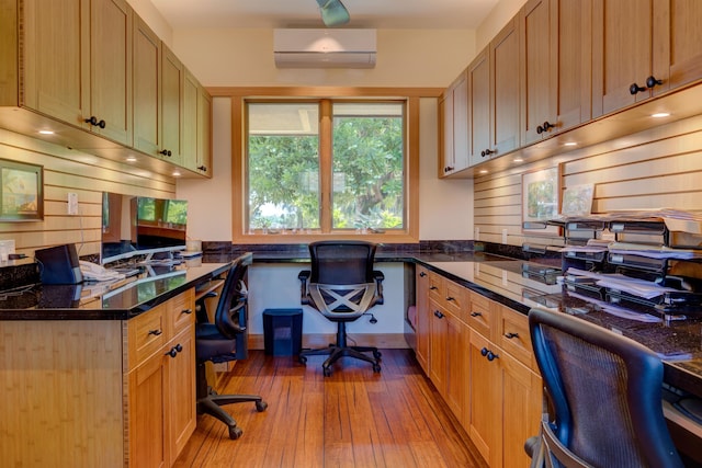 home office featuring built in desk, light hardwood / wood-style flooring, and a wall mounted air conditioner