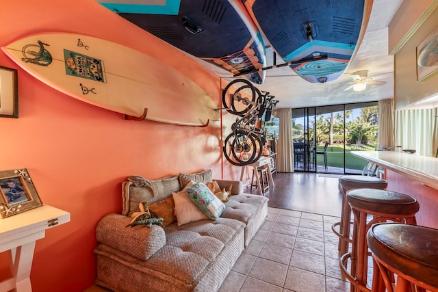 tiled living room with ceiling fan and a wall of windows