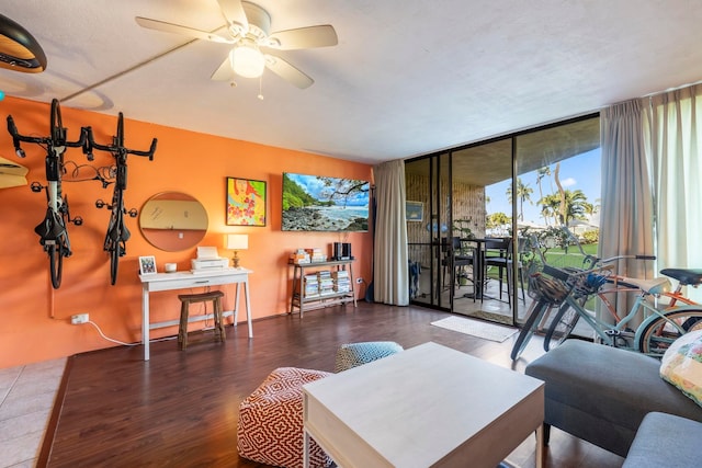 living room featuring dark wood-type flooring, a wall of windows, and ceiling fan