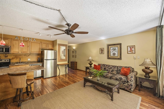 living room with a textured ceiling, ceiling fan, sink, and dark wood-type flooring