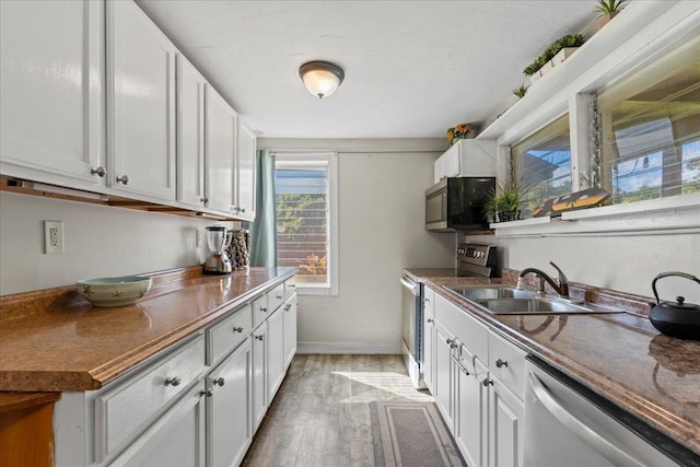 kitchen featuring white cabinetry, sink, stainless steel appliances, and light wood-type flooring