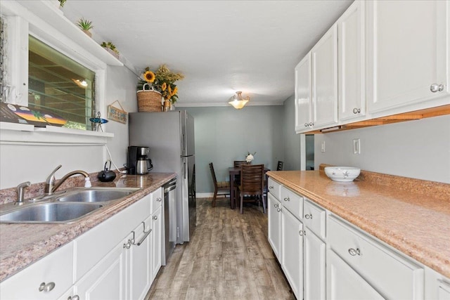 kitchen with white cabinetry, sink, stainless steel dishwasher, and light hardwood / wood-style flooring