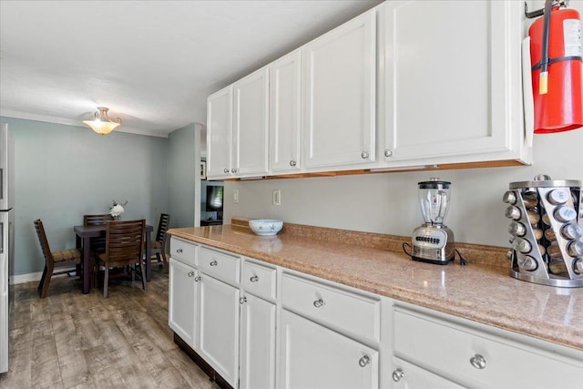 kitchen featuring white cabinets, light stone countertops, and light hardwood / wood-style flooring