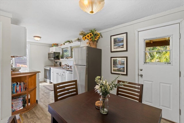 dining area featuring sink, a textured ceiling, and light wood-type flooring