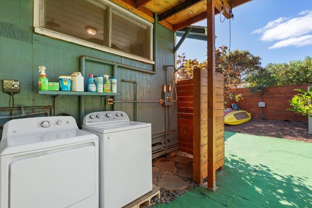 clothes washing area with washer and clothes dryer and wooden walls