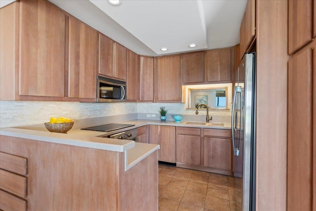 kitchen featuring backsplash, kitchen peninsula, sink, and appliances with stainless steel finishes