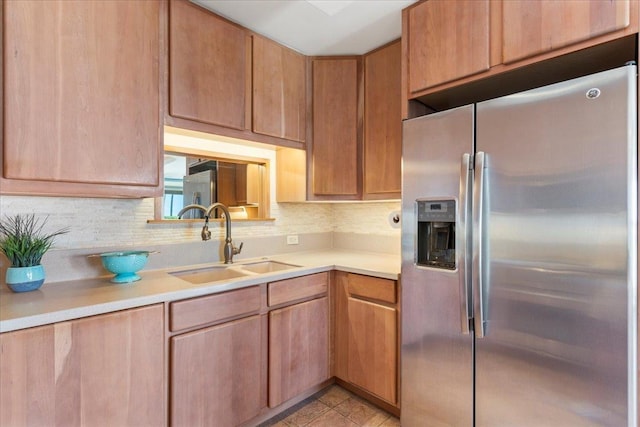 kitchen featuring decorative backsplash, stainless steel fridge, sink, and light tile patterned floors