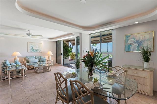 dining room with a raised ceiling, ceiling fan, and light tile patterned floors