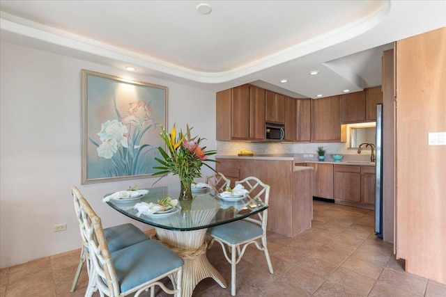 kitchen featuring a raised ceiling, decorative backsplash, sink, and light tile patterned flooring