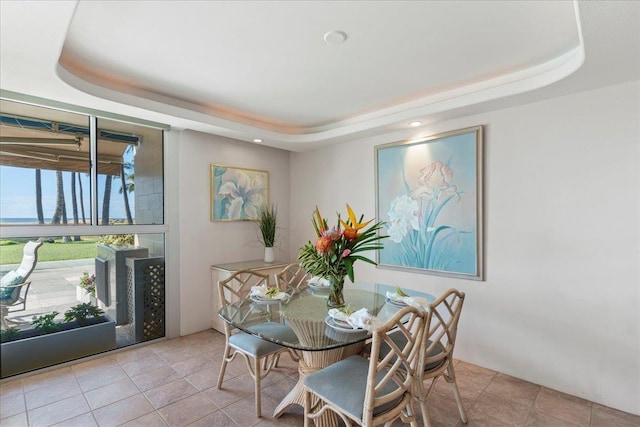 tiled dining space featuring a tray ceiling