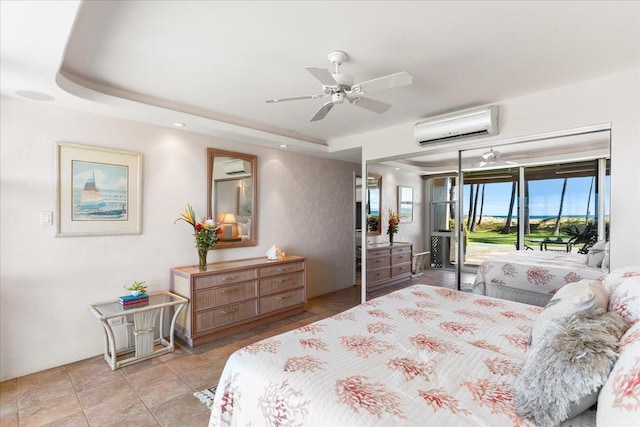 bedroom with a wall unit AC, access to exterior, ceiling fan, and a tray ceiling