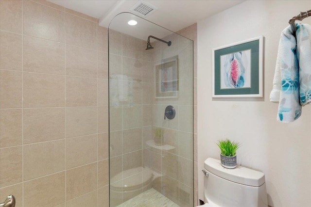 bathroom featuring tiled shower and toilet