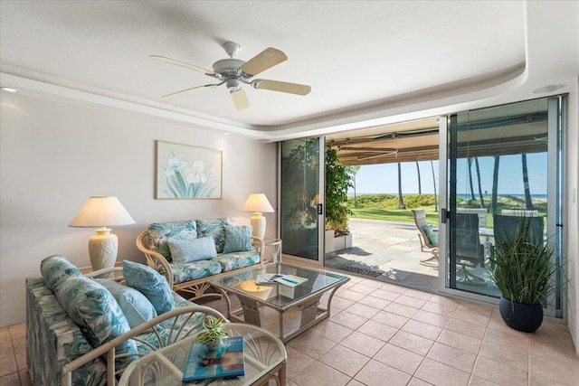 living room featuring ceiling fan, expansive windows, a raised ceiling, and light tile patterned floors