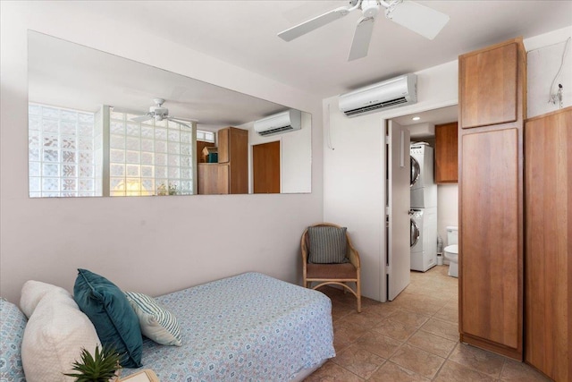 bedroom featuring ensuite bath, ceiling fan, a wall mounted air conditioner, and stacked washer and clothes dryer