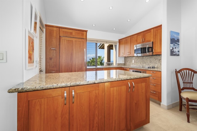 kitchen with backsplash, light stone counters, vaulted ceiling, and sink