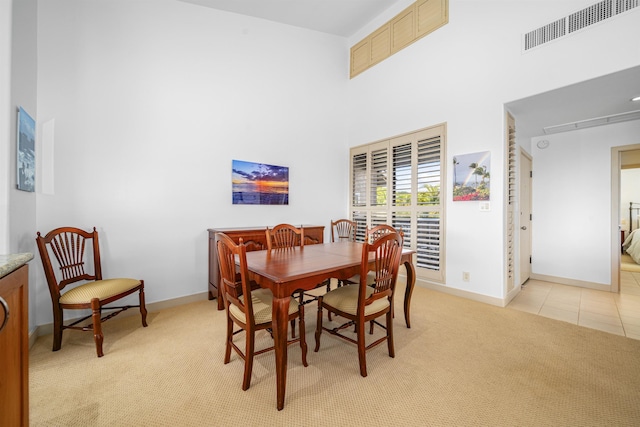 dining room featuring a high ceiling and light colored carpet