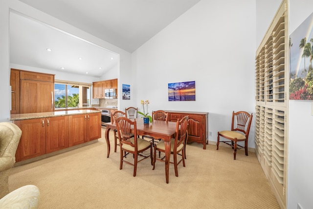 carpeted dining space featuring high vaulted ceiling