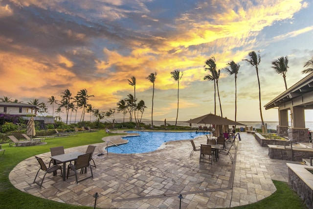 pool at dusk featuring a yard and a patio